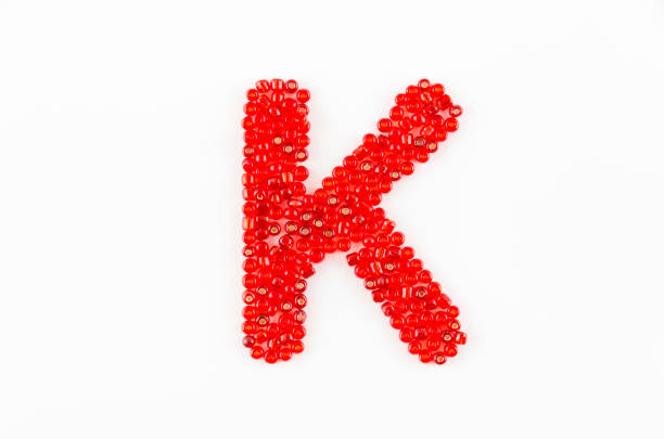 Alphabet of red beads on white background K