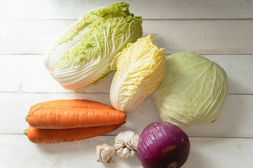 Carrots, garlic, onions, Chinese cabbage, and cabbage on a white board