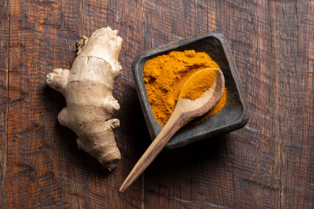 istock Ginger root and turmeric powder on a rustic wood top view 1489273481