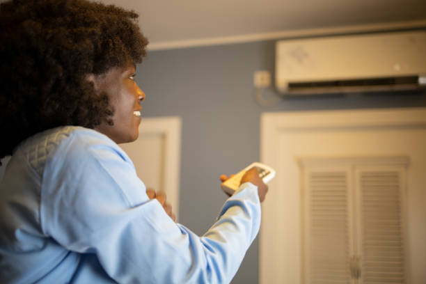 istock Woman turning on air conditioner 1489277732