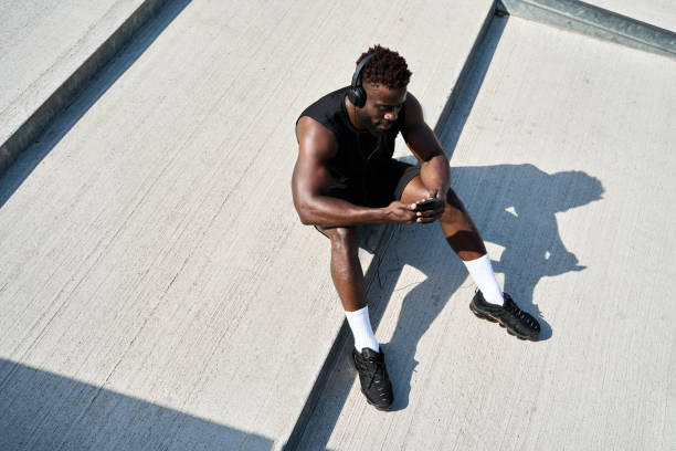 hombre negro joven deportista en forma que usa música para escuchar el teléfono durante el entrenamiento callejero. - 7583 fotografías e imágenes de stock