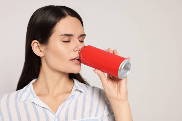 istock Beautiful young woman drinking from tin can on light grey background 1489279794