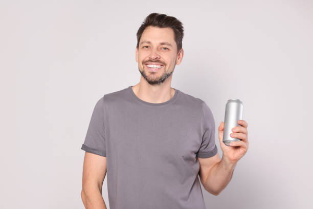 istock Happy man holding tin can with beverage on light grey background 1489279838