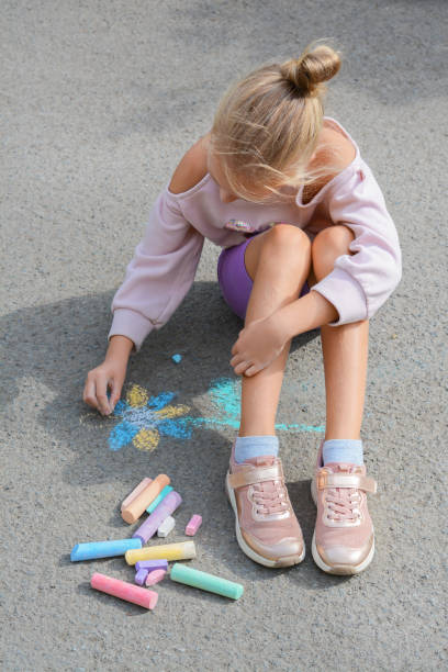 istock Little child drawing flower with chalk on asphalt 1489280042