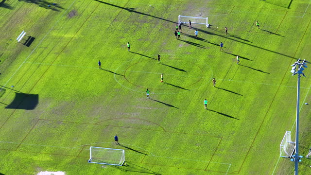 Aerial view of young adult amateur sportsmen playing soccer on grass covered sports stadium. Concept of active lifestyle