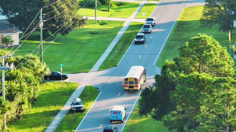 Top view of standard american yellow school bus picking up kids at rural town street stop for their lessongs in early morning. Public transport in the USA