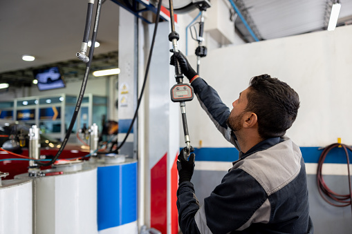 Latin American mechanic changing the oil on a car at an auto repair shop