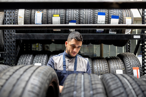 Latin American mechanic selecting a tire from the stock at an auto repair shop