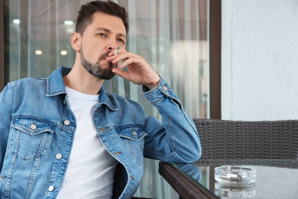istock Handsome man smoking cigarette at table in outdoor cafe 1489287760