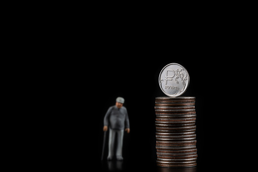 Conceptual plot about pension savings in Russia with a figurine of a pensioner and a coin with the symbol of the Russian ruble