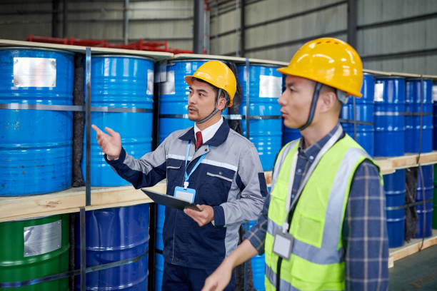 two asian male examining & discussing in chemicals warehouse - toxic waste toxic substance drum barrel imagens e fotografias de stock