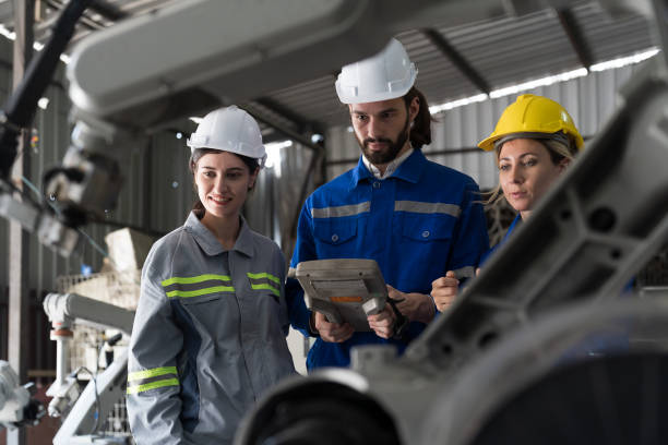 istock Industrial Manufacturing Robotic Arms. Male and female engineer worker control autonomous robotics arms welding machine for manufacturing lines in production plant factory 1489316113
