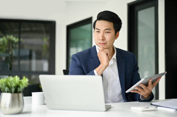 istock Thoughtful Asian businessman looking at laptop screen, planning a new project 1489316748