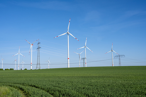Power lines and wind turbines in a green agricultural landscape