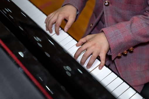 A pair of boy's hands are playing the piano