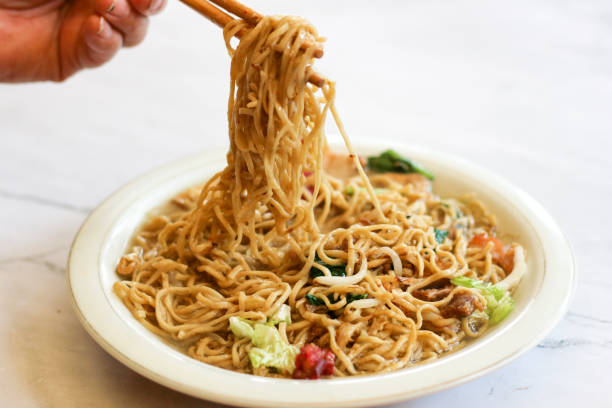 istock female hand taking noodles in a plate with chopsticks. 1489337242