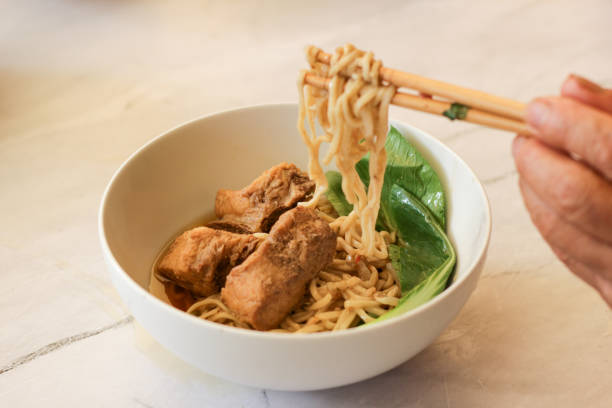istock hand holding chopstick and take bak kut teh in bowl. 1489337974