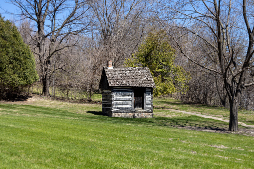 This image shows a rustic 19th century single room log cabin in a rural area in the Midwestern United States.