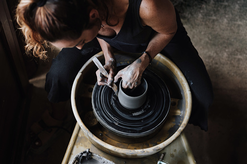 hands of latin woman potter, creating a clay pot on a pottery wheel in her workshop in Mexico Latin America, hispanic female