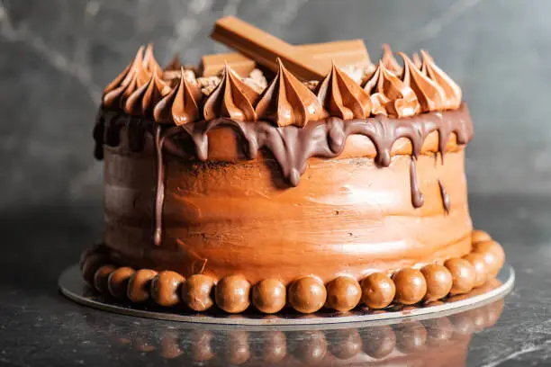 Deliciously moist Chocolate Mud Cake with whipped ganache, milk chocolate drip and decoration.