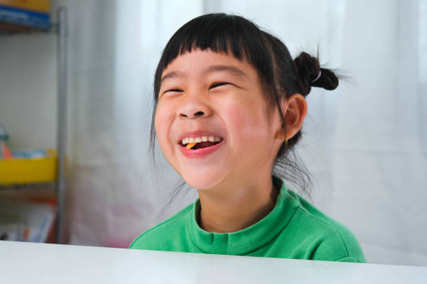 счастливая милая маленькая девочка ест желатиновые конфеты. забавный малыш с жевательной резинкой. красивая маленькая девочка с витаминам - chewy стоковые фото и изображения