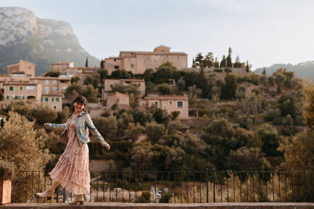 Happy woman with brown hair walking in front of the old rustic and famous village Deiá stock photo