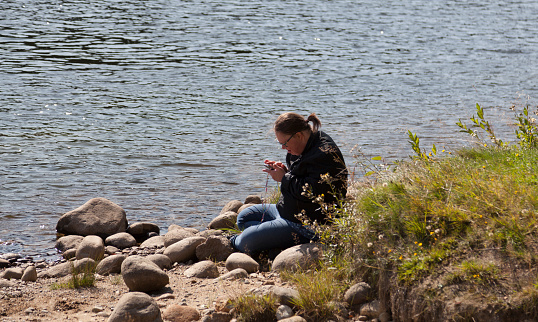 Skelleftea, Norrland Sweden - August 22, 2019: disabled man sitting by the river with phone