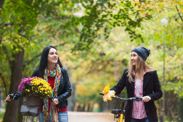 istock Two women pushing bikes in park and talking 1489353883