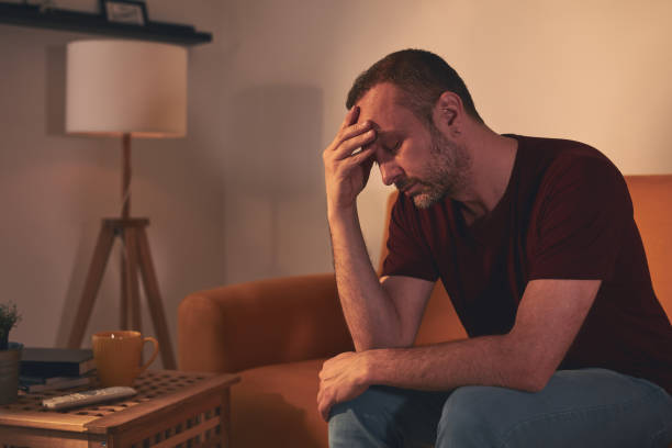 istock Man with headache sitting on a sofa at home. 1489355203