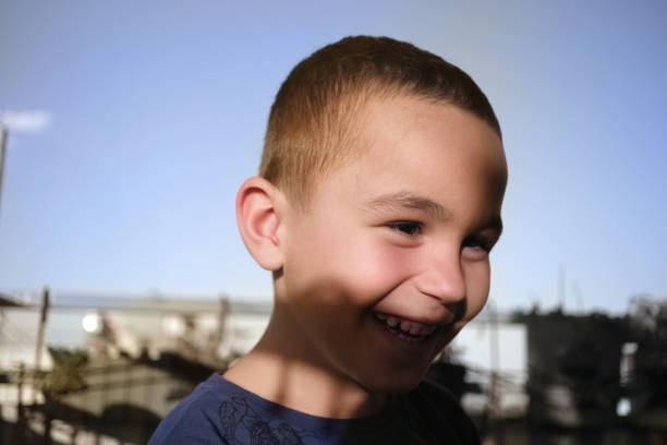 Portrait of a 5 year old boy. Keeping in touch with his family. On the balcony of the house. Taken at sunset. Cheerful boy laughing