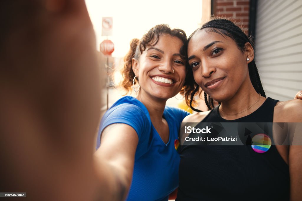 Friends take a selfie LGBTQIA+ concept, two friends with a rainbow pin on the t-shirt taking a selfie. Activist Stock Photo