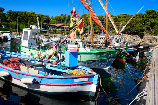 A fishing boat moored in a harbor by the Côte dAzur, its nautical vessel glistening against the blue sky and vast body of water. A dependable mode of transportation.