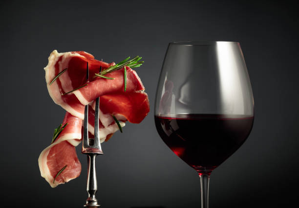 Glass of red wine and sliced prosciutto with rosemary. stock photo