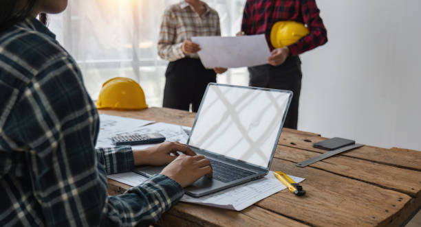 istock Team of structural engineers working in office looking at laptop discussing design of building plan 1489362487