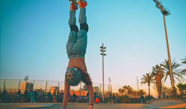 Photo of A young woman roller skating and jumping on a ramp at a skatepark outside. A skilled skater riding around outdoors. Practicing her rollerblading tricks or technique for a competition or race