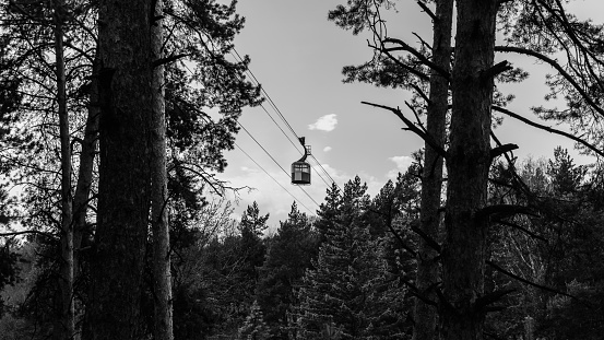 Cable car in the forest with sky, clouds, and trees.