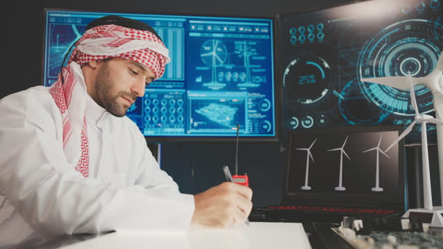 Young man Middle East working at a computer screen. He’s working on software looking at the arrangement of wind turbines on a wind farm.