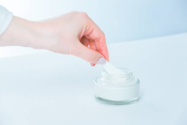 Woman hands taking moisturizer cream from jar stock photo