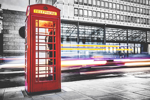 London red telephone booth on city street. Red in black and white