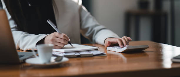 istock businesswoman or accountant taking note and working on calculator and laptop computer to calculate business data during make note at notepad, accountancy document at office. 1489367911