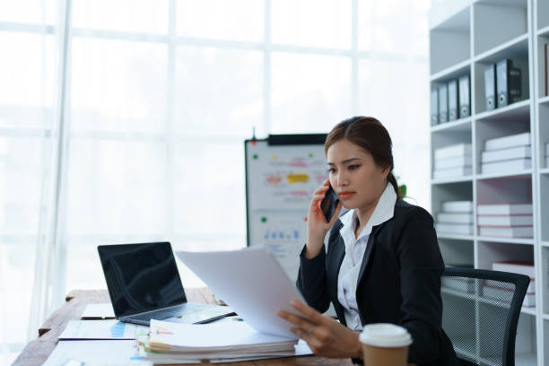 Busy businesswoman wearing a suit busy with work workaholic while sitting at work clear paperworks with documents and talk on the phone on your smartphone hear the hustle and bustle, busy concepts mujer de negocios ocupada con un traje ocupado con el trabajo adicto al trabajo mientras está sentada en el trabajo papeleo claro con documentos y habla por teléfono en su teléfono inteligente escuche el ajetreo y el bullicio, conceptos ocupados.