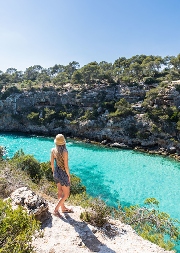 Rear view of woman with long blonde hair in cala pi, Mallorca, balearic islands. Turquoise water rounded by rocks