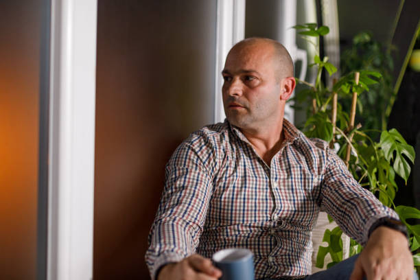 istock Man sitting on the window sill, enjoying coffee and looking outside 1489384094