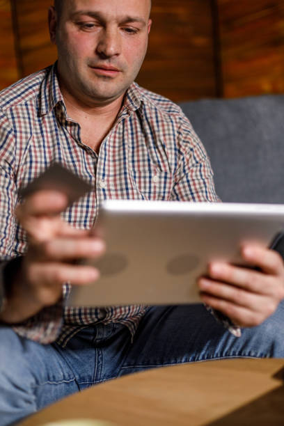 istock Man lounging on the sofa and online shopping via digital tablet 1489384191