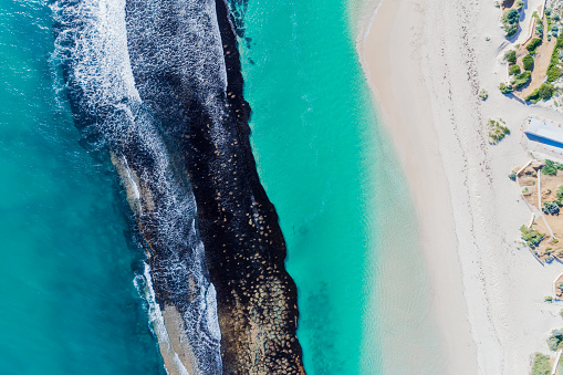Summer seascape beautiful waves, blue sea water in sunny day. Top view from drone. Turquoise sea aerial view of reef, amazing tropical nature background. Beautiful bright sea waves splashing and beach sand sun light. Yanchep Reef, Western Australia.