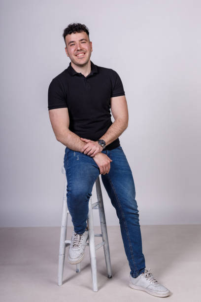 istock Charming young man sitting against white background, smiling with confidence 1489388652