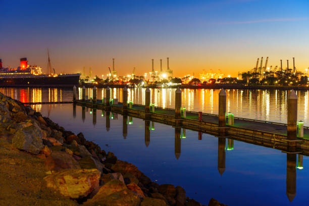 Vibrant colors and dazzling lights of Long Beach Harbor at night, with the picturesque pier and Queen Mary adding to the scene's magical ambiance.