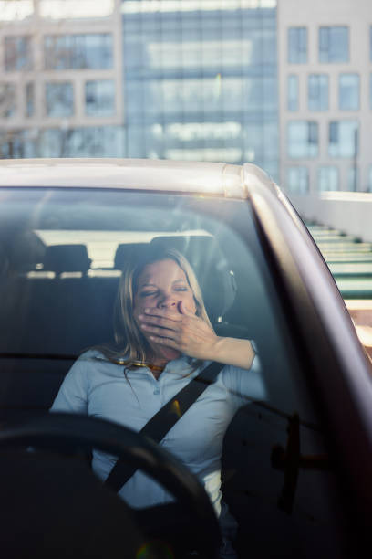 istock Tired businesswoman yawning while driving a car. 1489392376