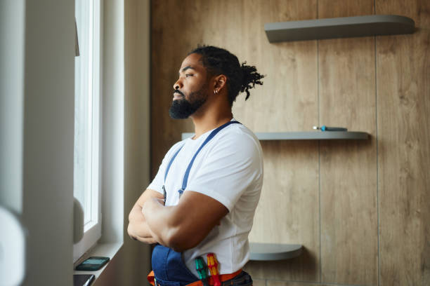 istock Thoughtful black worker looking through window from renovating apartment. 1489394028