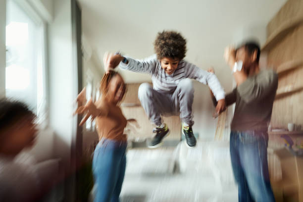 Carefree African American boy having fun while jumping after relocating with his family into a new apartment. Blurred motion.